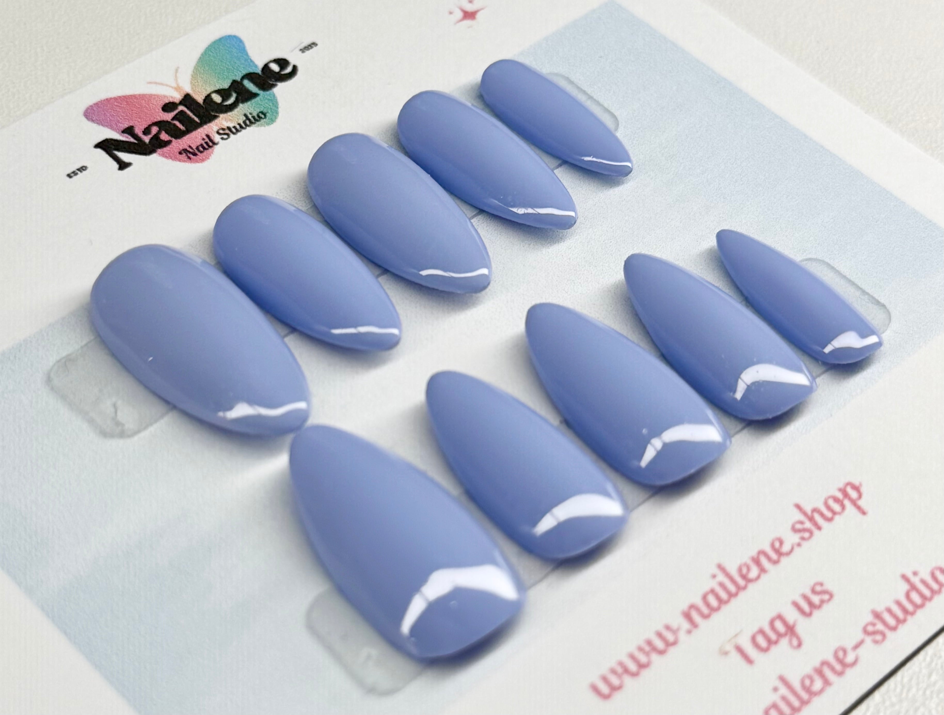 Set of blue nail extensions on a display card with Nailene Studio branding.
