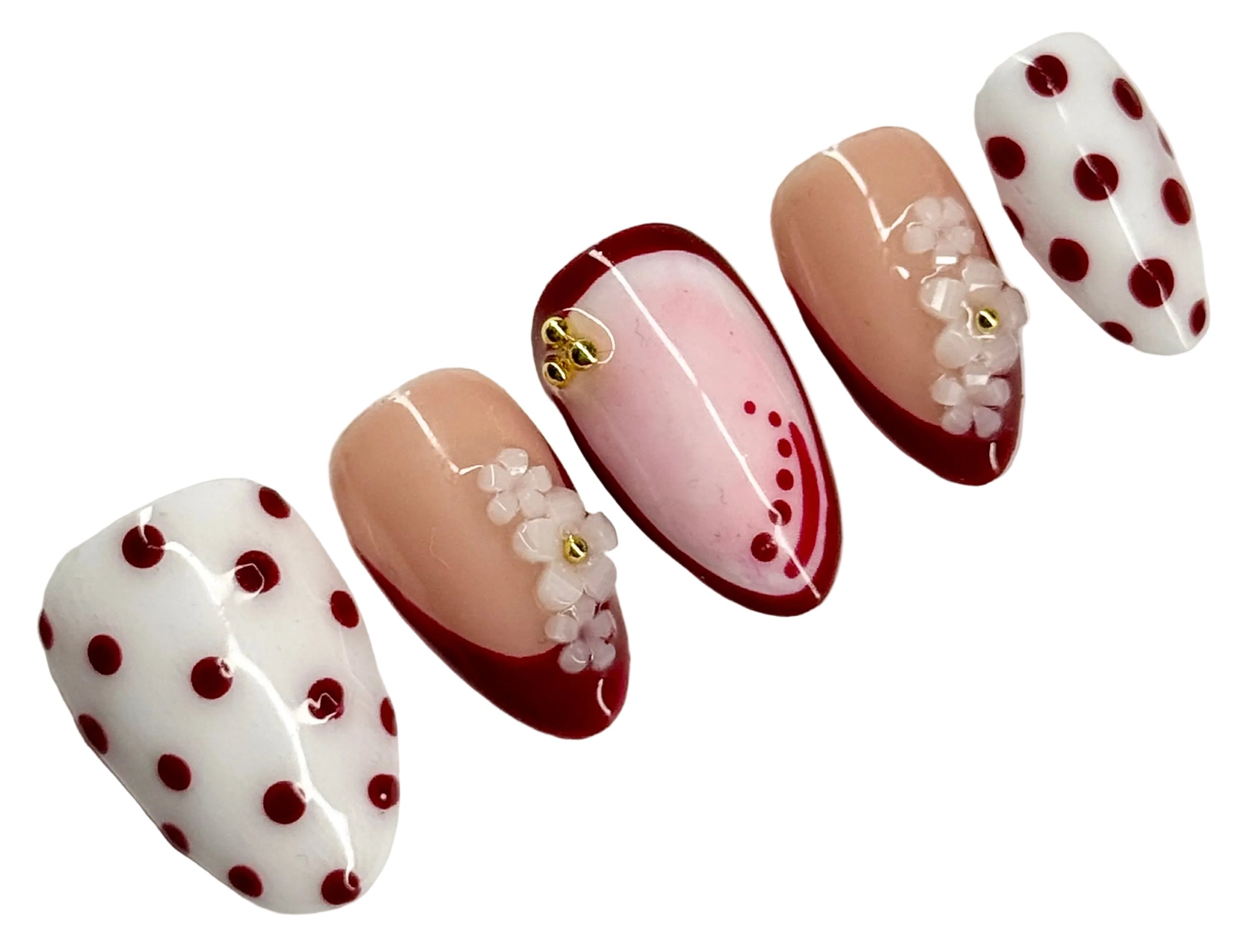 Nail art with polka dots and floral designs on a white background