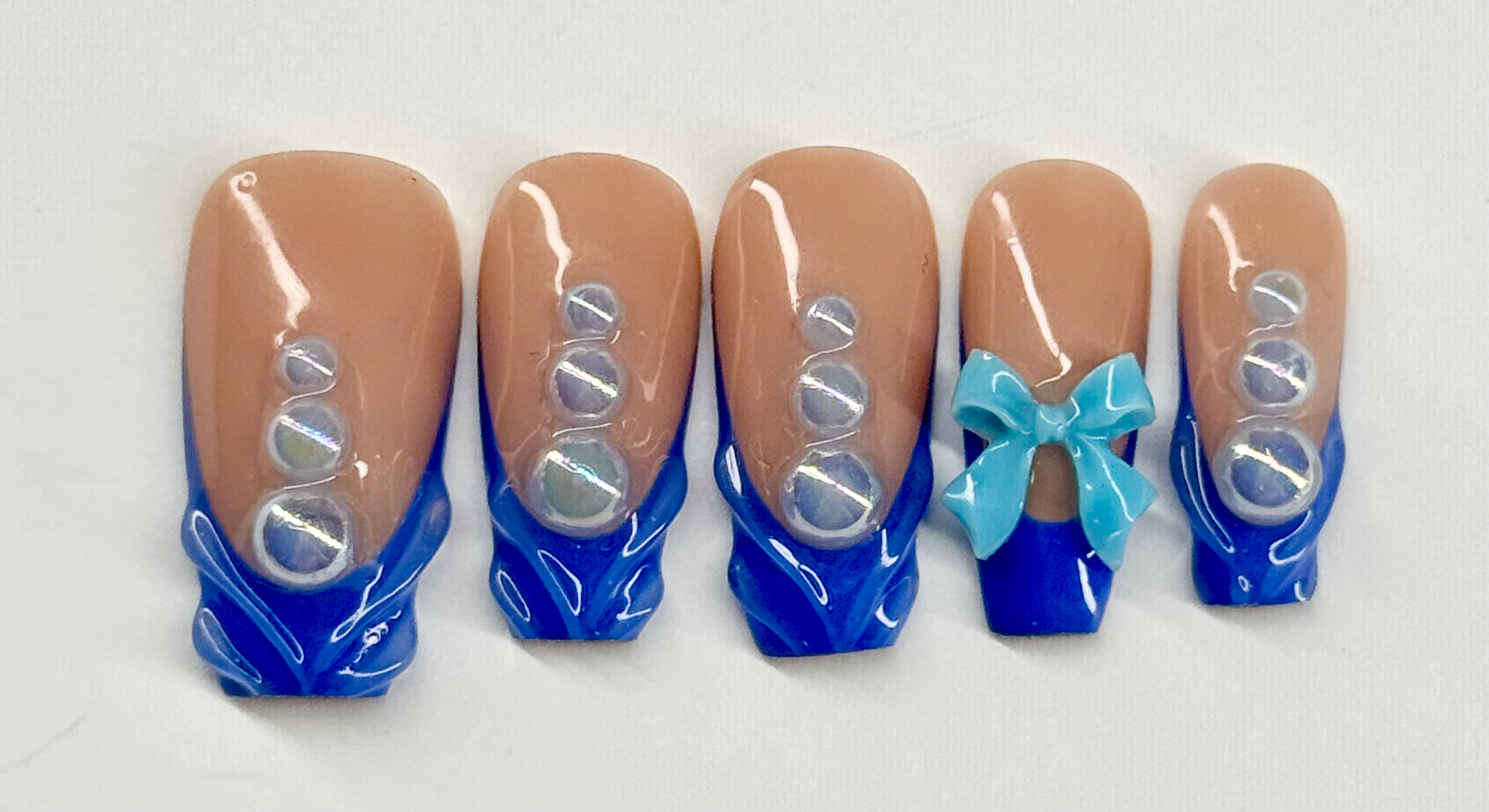 Set of false nails with blue and brown design on a white background
